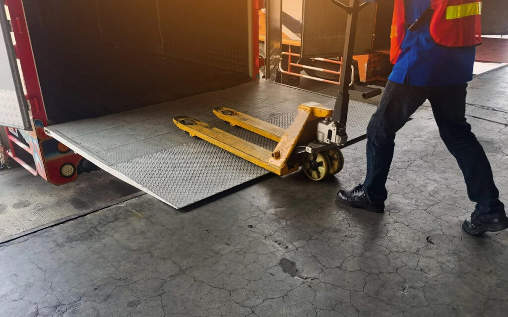loading dock with man rolling a pallet jack into the back of a truck