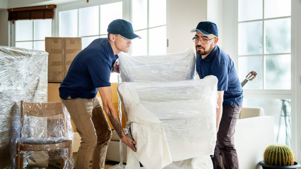 Two movers moving a chair wrapped in plastic