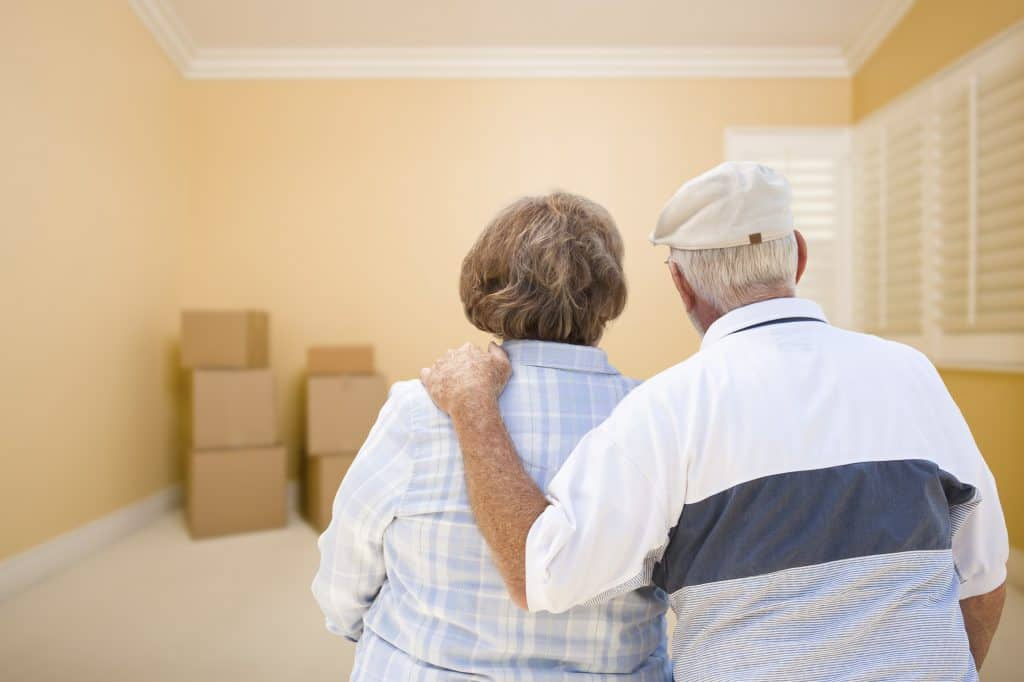 senior couple looking at moving boxes in livingroom